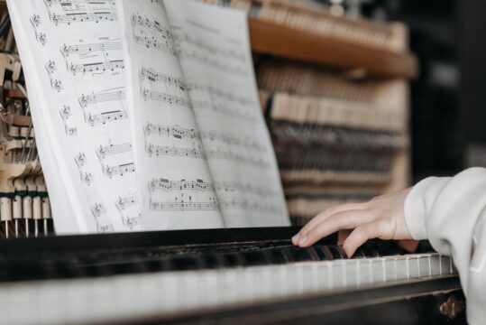 النوتة الموسيقية مع شخص يعزف على البيانو - Musical Note and a person plays the piano Photo by Pavel Danilyuk: https://www.pexels.com/photo/fingers-on-piano-keys-with-music-sheet-7521227/